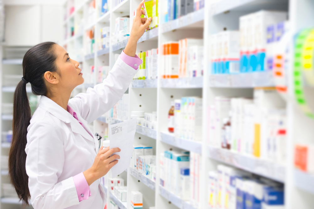 pharmacist looking at wall of meds